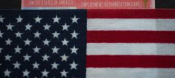 An employment authorization card is partially visible behind a folded United States flag, symbolizing hope and guidance from a Chicago Immigration Attorney.